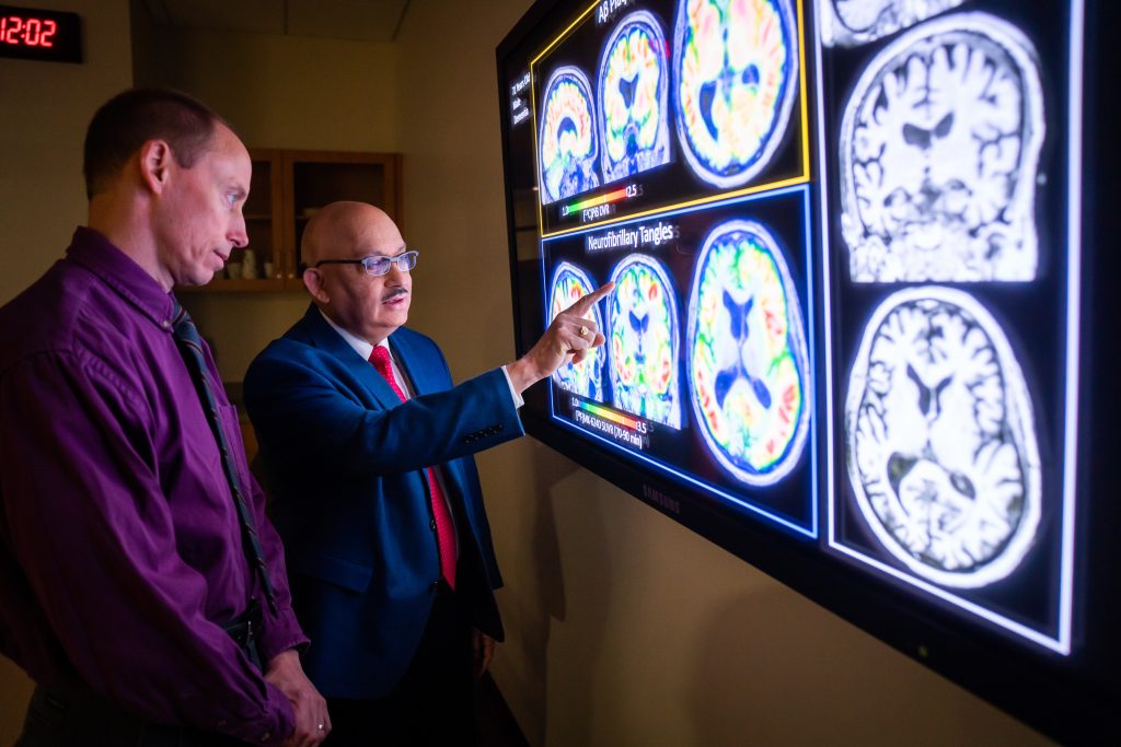 Dr. Sanjay Asthana points something out in a PET scan out to Dr. Steve Barczi