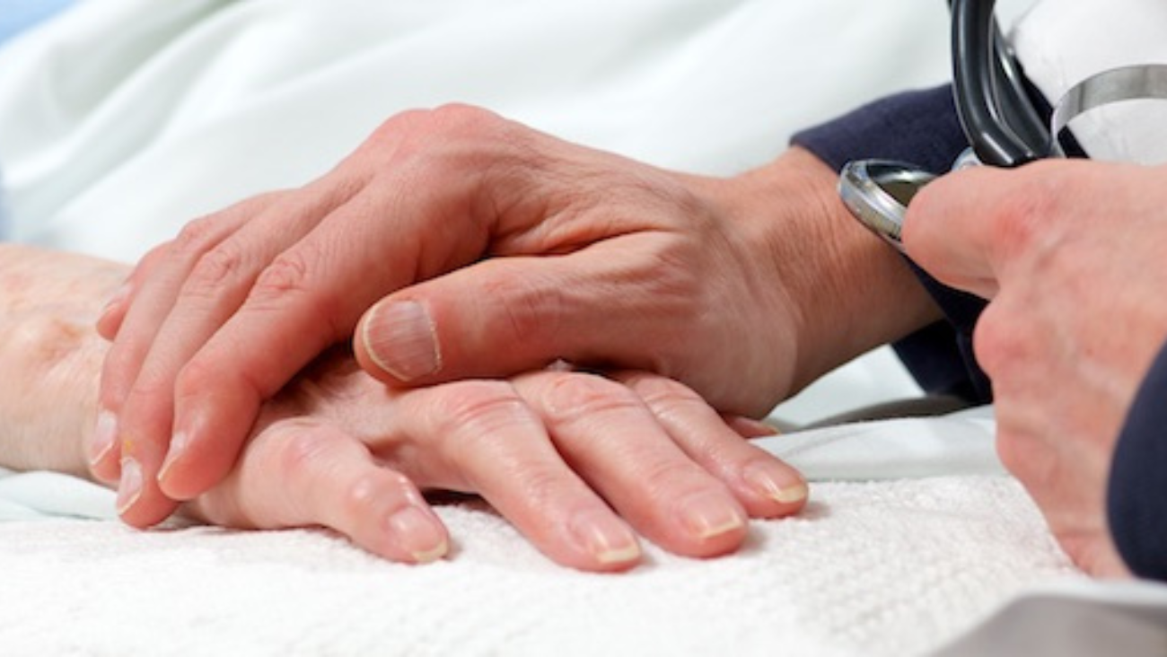 A close up of a doctor resting their hand on a patient's supportively