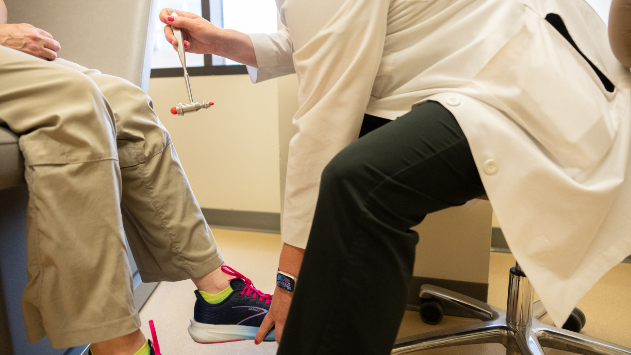 A nurse tests a patient's knee reflexes at an appointment