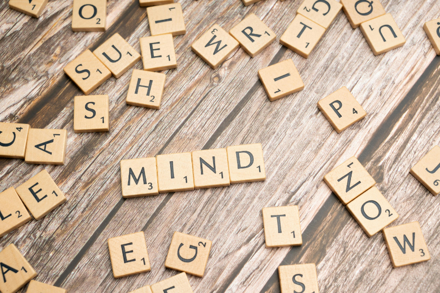 A handful of letter tiles are scattered on a table. A few in the middle spell out 'MIND'